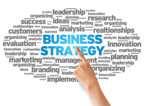 Hand pointing at a Business Strategy Word Cloud on white background.